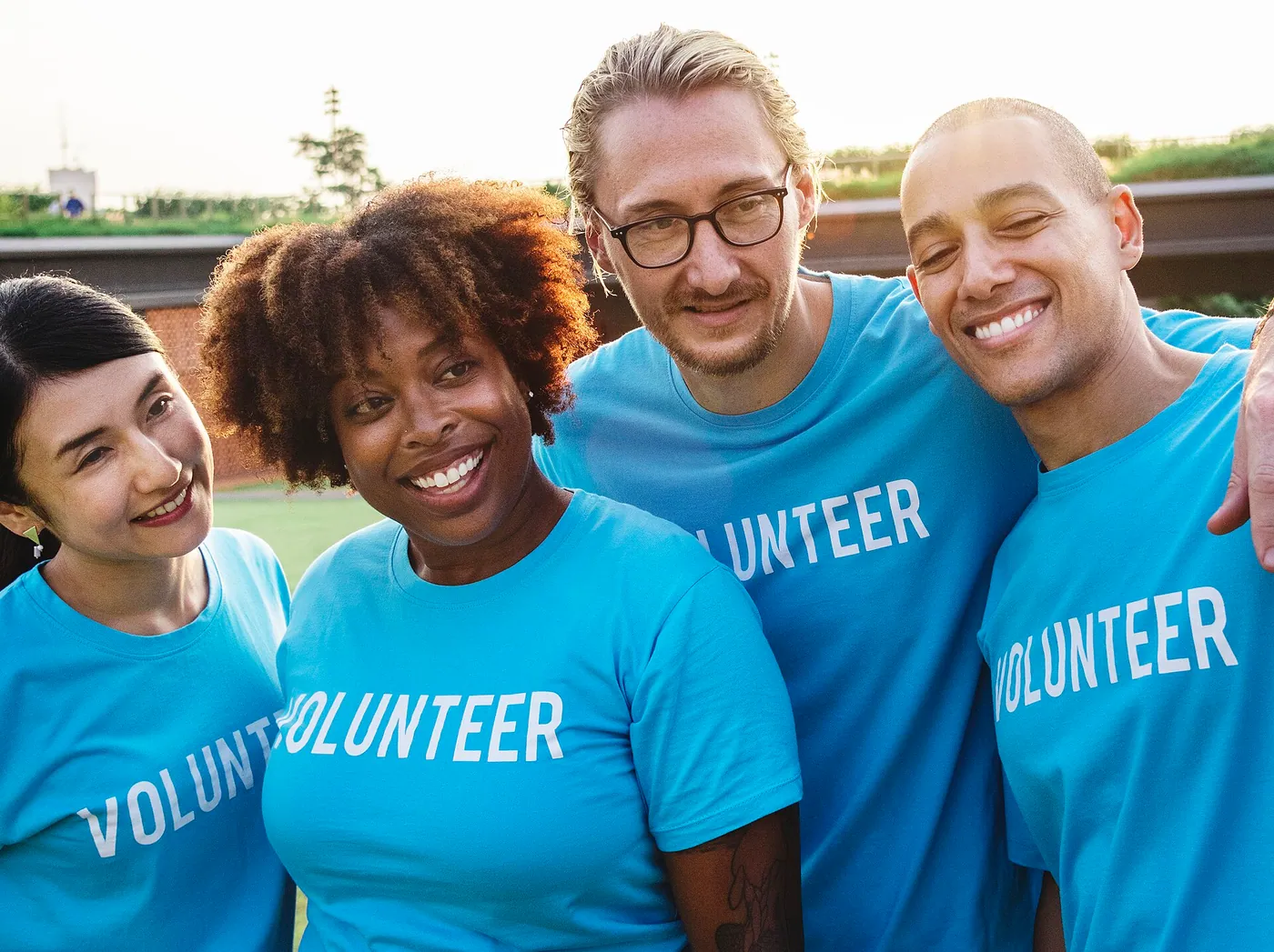 A smiling multi-ethnic group of volunteers standing together outdoors.